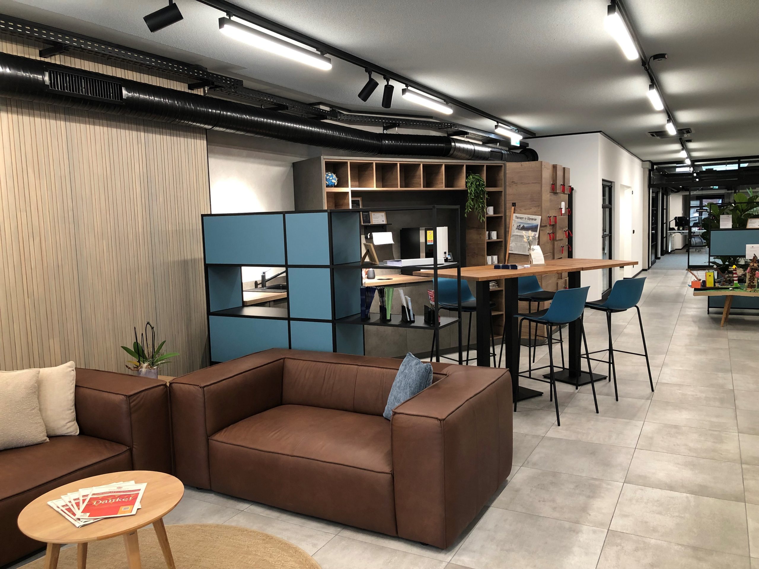Ein moderner Bürobereich mit einem Sitzbereich und Arbeitsplätzen, ausgestattet mit Tischen und Stühlen.