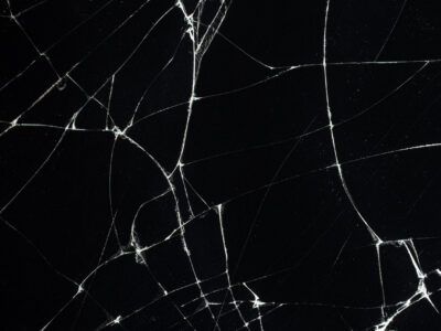 Schwarze Oberfläche mit Rissen Schwarze Oberfläche mit feinen, weißen Rissen, die ein komplexes Muster bilden.