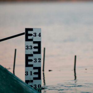 Wasserstandsanzeiger am See Wasserstandsanzeiger mit Markierungen am Ufer eines Sees bei Sonnenuntergang.