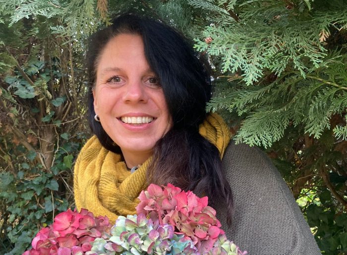Frau mit langen schwarzen Haaren hält einen Strauß bunter Hortensien in den Händen.