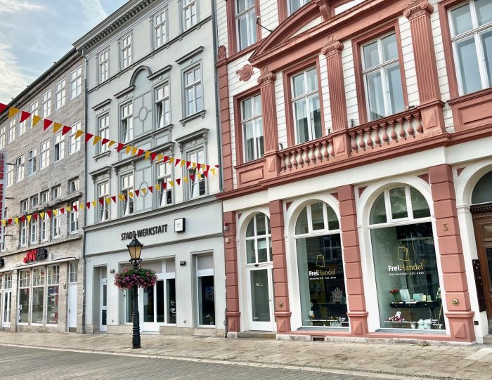 Fassaden von historischen Gebäuden mit bunten Fahnen in einer Stadtstraße.