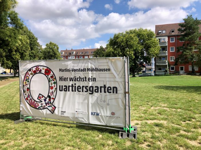 Banner mit der Aufschrift 'Hier wächst ein Quartiersgarten' in Mühlhausen, Deutschland.