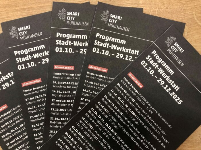 Mehrere schwarze Flyer mit Informationen zum Programm Stadt-Werkstatt in Muhlhausen für 2025.