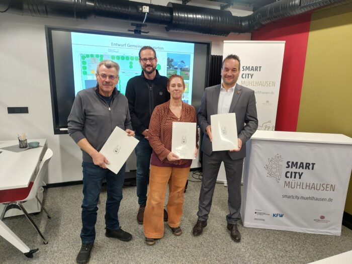Vier Personen halten Dokumente bei der Smart City Mühlhausen Veranstaltung in einem modernen Raum.