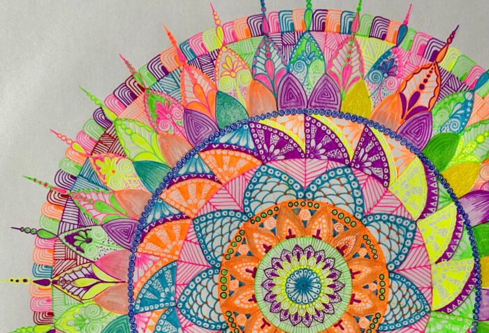 Farbenfrohe Mandala-Zeichnung mit konzentrischen Kreisen, geometrischen Mustern und feinen Linien in Orange, Blau, Grün, Pink und Lila auf hellem Hintergrund